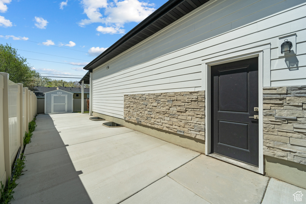 View of side of home featuring a patio area and a storage unit