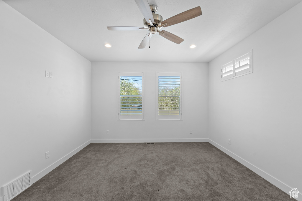 Spare room featuring dark colored carpet and ceiling fan