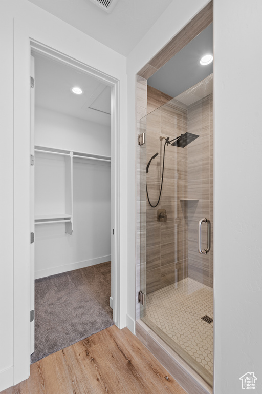 Bathroom featuring wood-type flooring and a shower with door