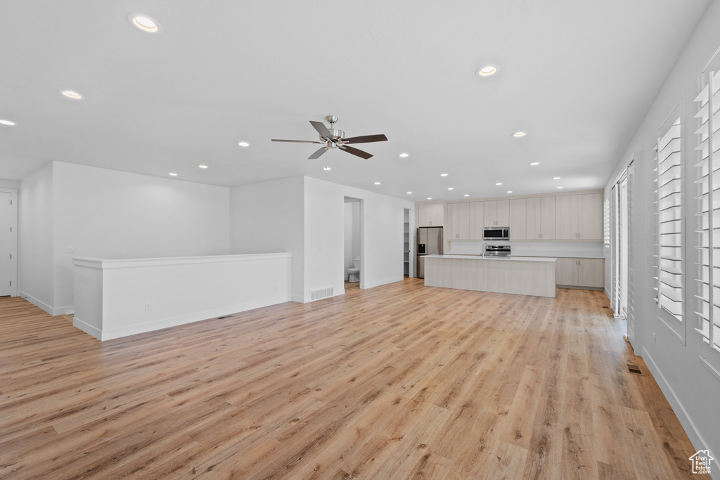 Unfurnished living room featuring light hardwood / wood-style floors, ceiling fan, and plenty of natural light