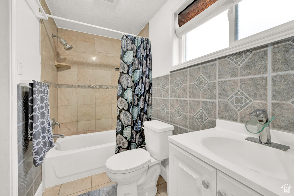Full bathroom with tile floors, tile walls, vanity, shower / tub combo with curtain, and toilet