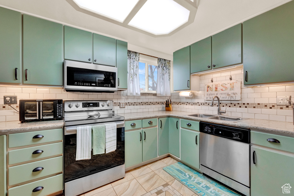 Kitchen with tasteful backsplash, stainless steel appliances, and light tile floors