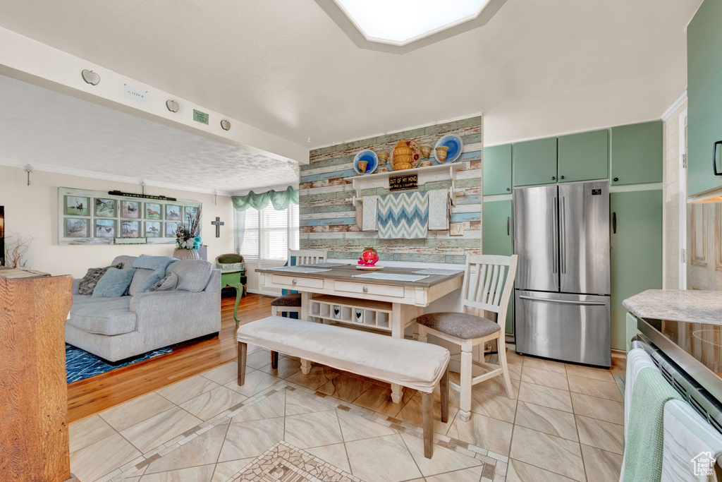 Kitchen featuring light hardwood / wood-style flooring, green cabinets, stove, tasteful backsplash, and stainless steel fridge