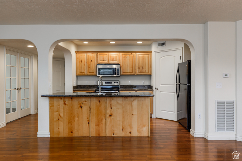 Kitchen featuring range, fridge, dark hardwood / wood-style flooring, sink, and dark stone counters