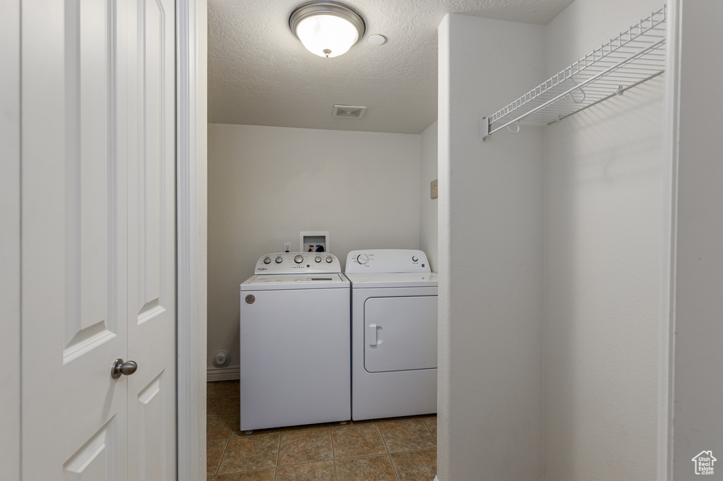 Laundry area with light tile floors, washer hookup, and washing machine and clothes dryer