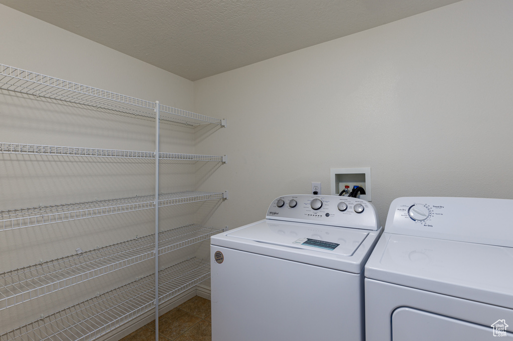 Washroom with dark tile flooring, washer hookup, and washing machine and clothes dryer