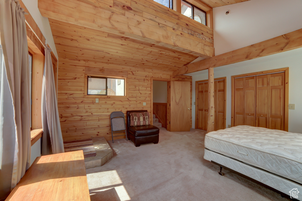 Bedroom with light colored carpet, wooden walls, and wood ceiling