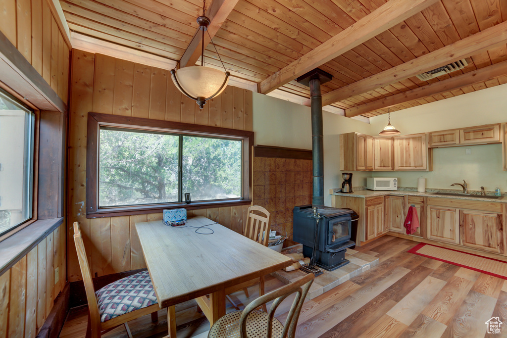 Dining area featuring a wood stove, beam ceiling, wooden ceiling, and light wood-type flooring