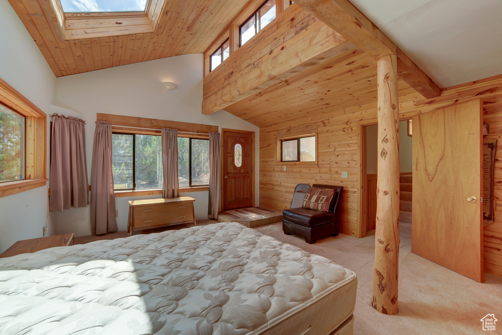 Bedroom with a skylight, beam ceiling, high vaulted ceiling, and light carpet