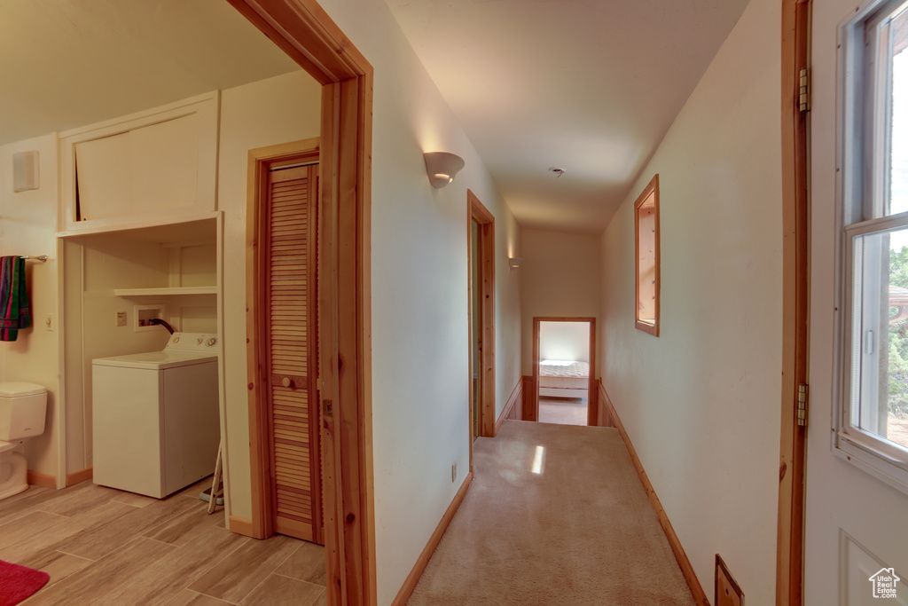 Corridor with light colored carpet and washer / clothes dryer
