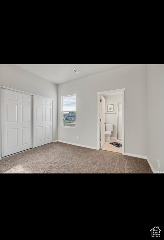 Unfurnished bedroom featuring light carpet and ensuite bath