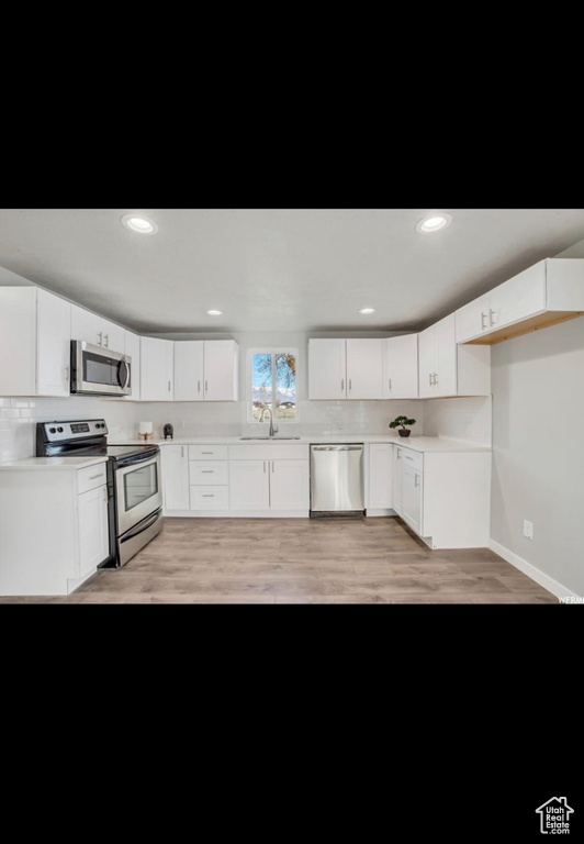 Kitchen featuring appliances with stainless steel finishes, light hardwood / wood-style flooring, sink, and white cabinets