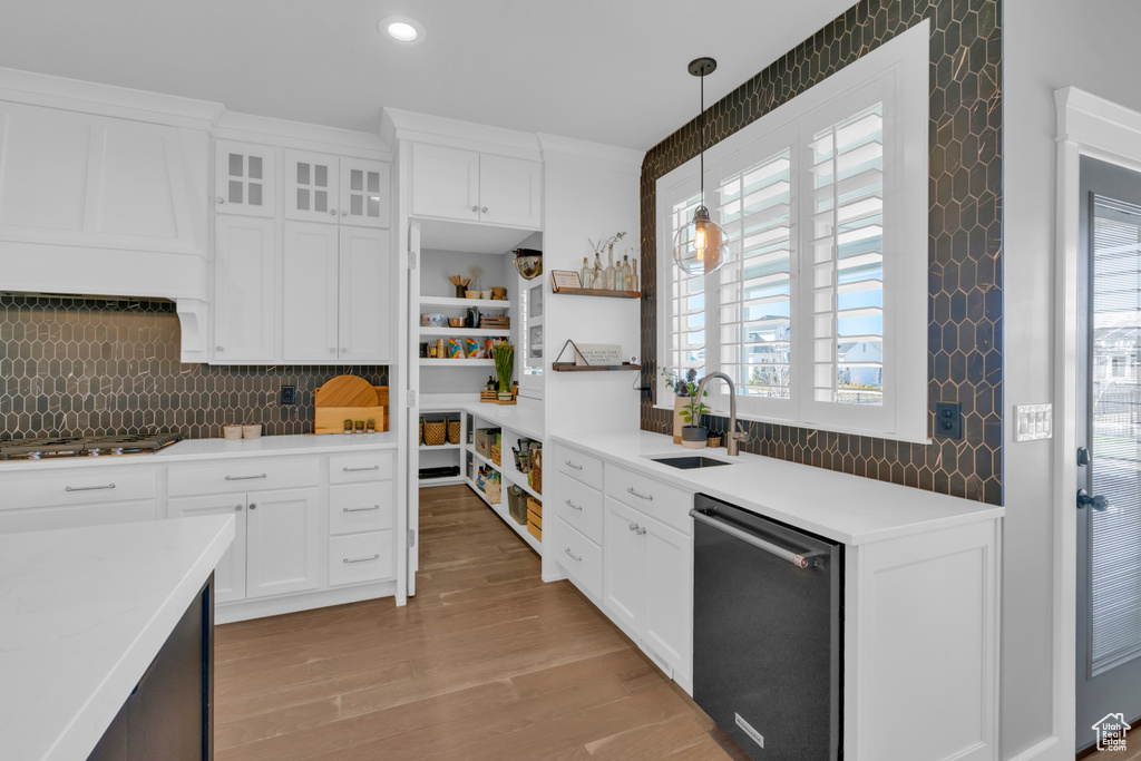 Kitchen with decorative light fixtures, white cabinets, backsplash, appliances with stainless steel finishes, and sink