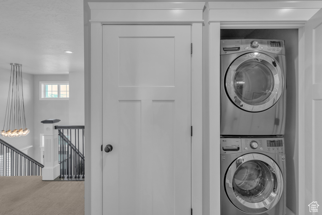 Laundry room with stacked washer and dryer and carpet floors
