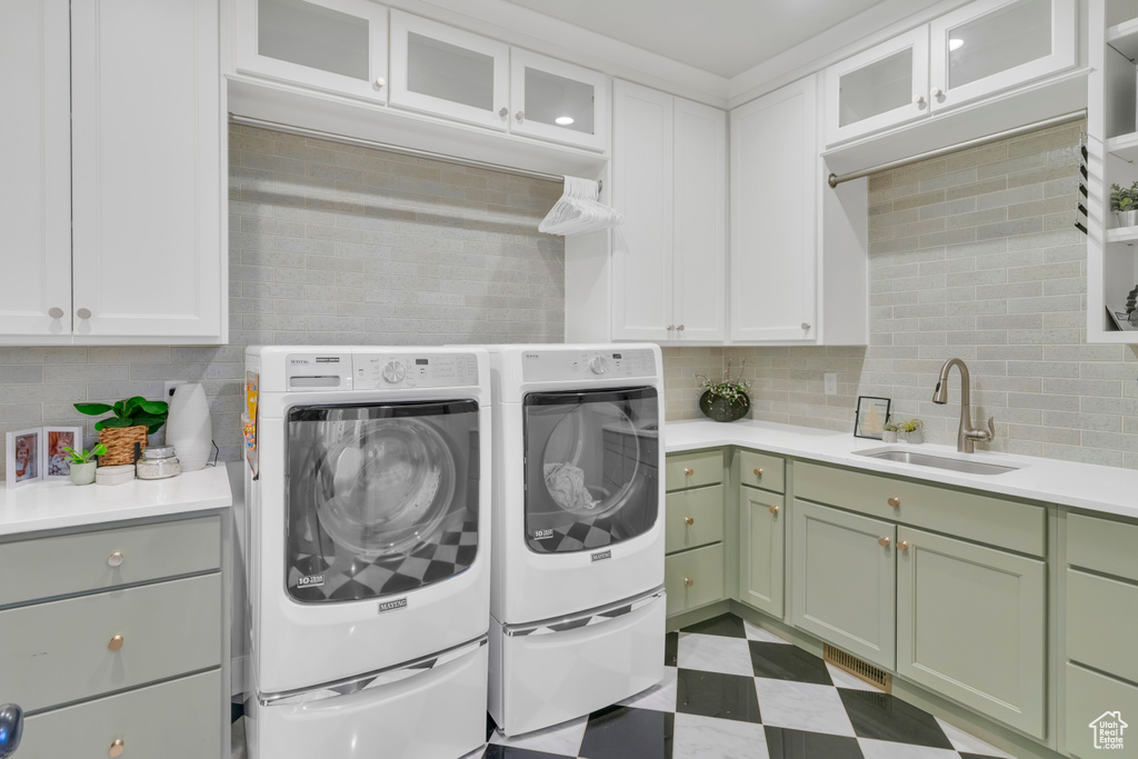 Clothes washing area with sink, light tile flooring, cabinets, and washer and clothes dryer