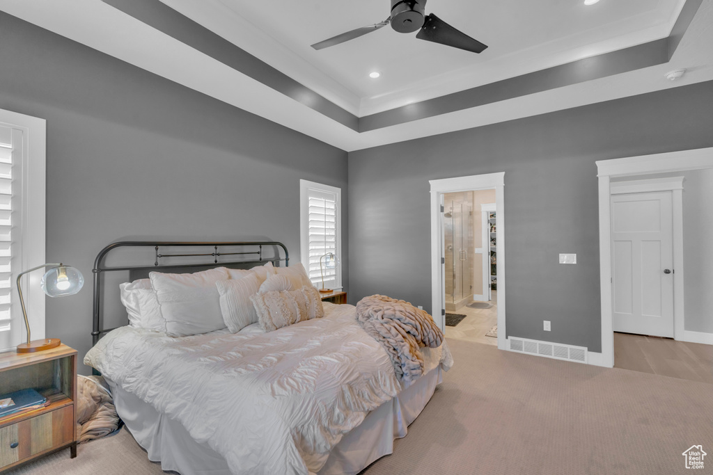 Carpeted bedroom featuring connected bathroom, ceiling fan, and a raised ceiling