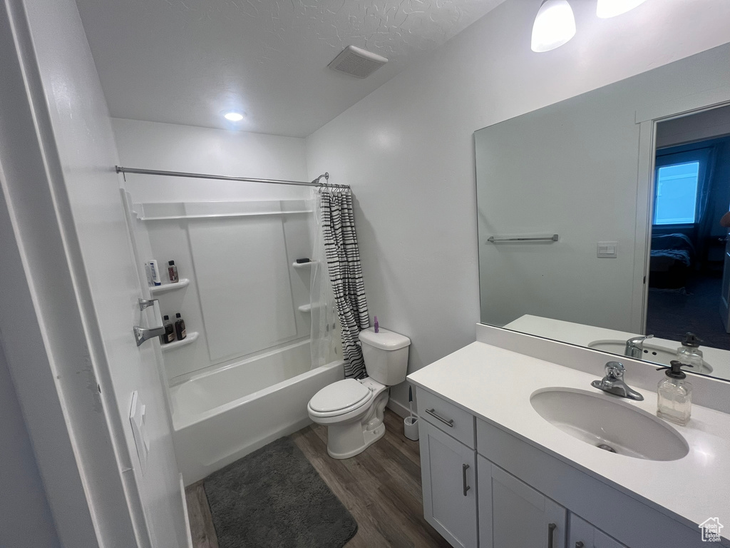 Full bathroom featuring wood-type flooring, vanity, shower / bath combo, and toilet