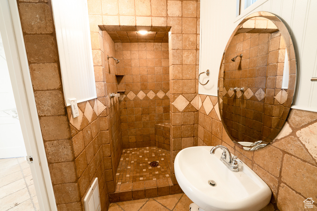 Bathroom featuring sink, a tile shower, and tile floors