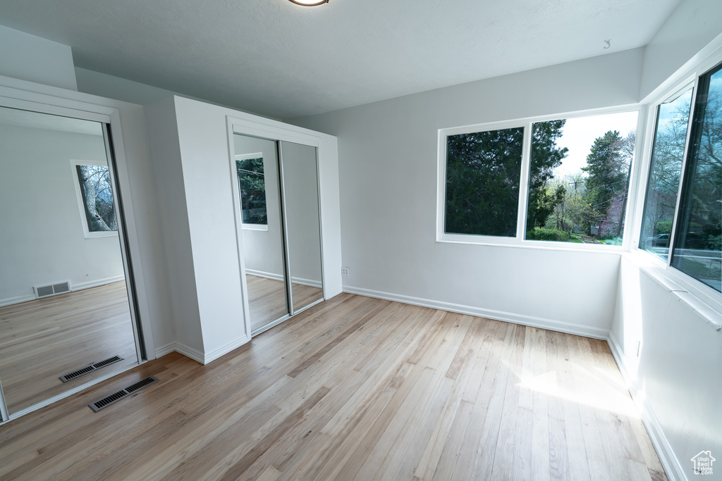 Unfurnished bedroom featuring a closet and light hardwood / wood-style floors