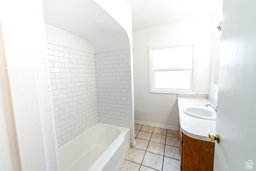 Bathroom with tiled shower / bath combo, vanity, and tile floors