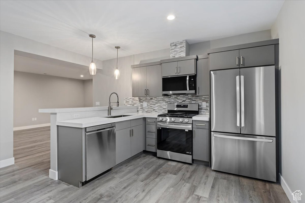 Kitchen featuring appliances with stainless steel finishes, light hardwood / wood-style flooring, sink, and kitchen peninsula