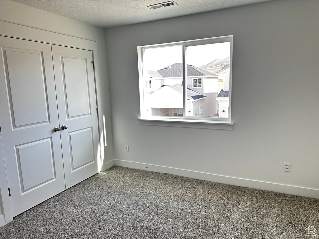 Carpeted empty room featuring plenty of natural light and a textured ceiling