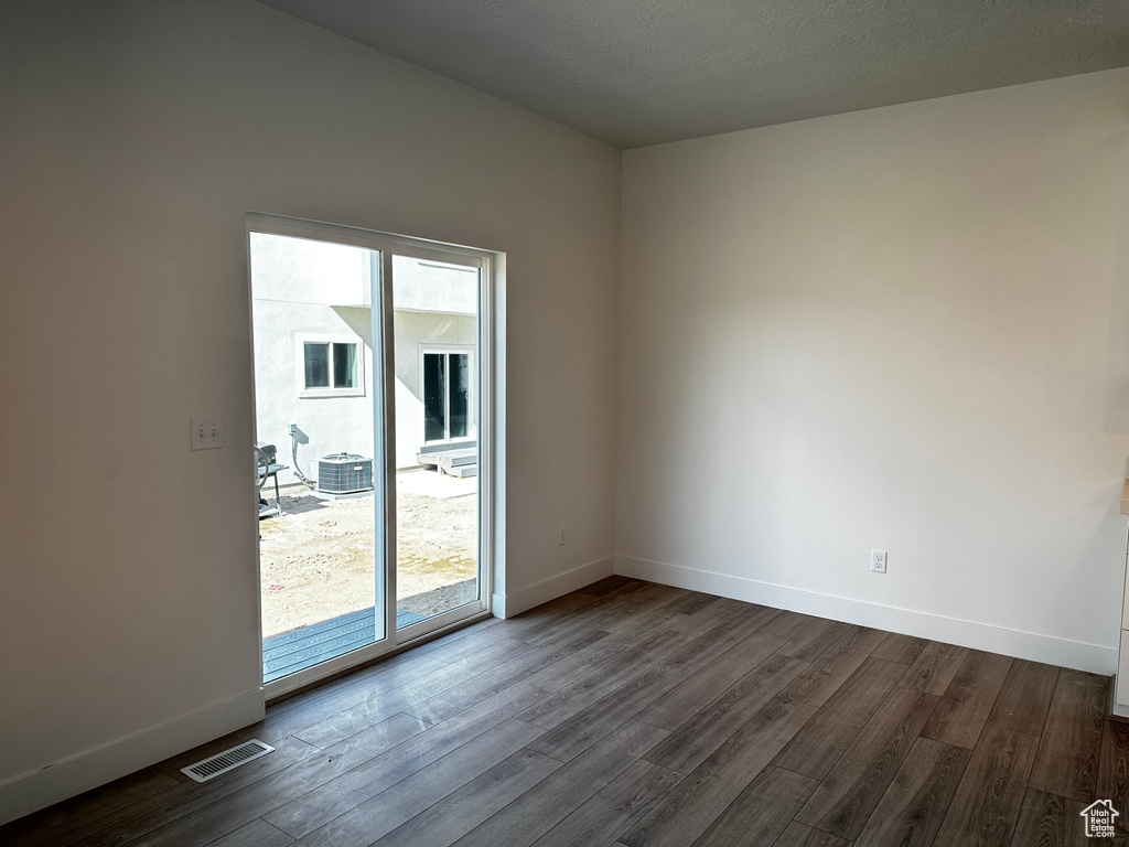 Empty room with dark hardwood / wood-style flooring, a healthy amount of sunlight, and a textured ceiling