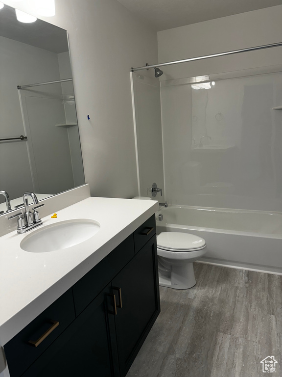 Full bathroom featuring wood-type flooring, oversized vanity, bathtub / shower combination, and toilet