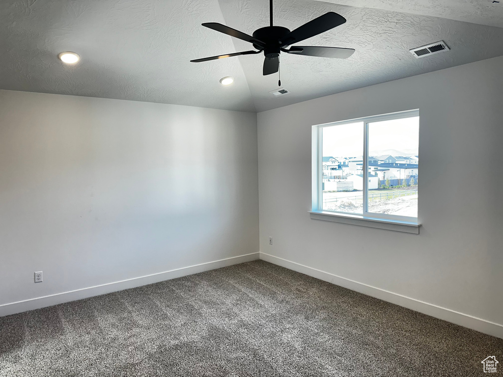 Carpeted spare room with ceiling fan, a textured ceiling, and lofted ceiling