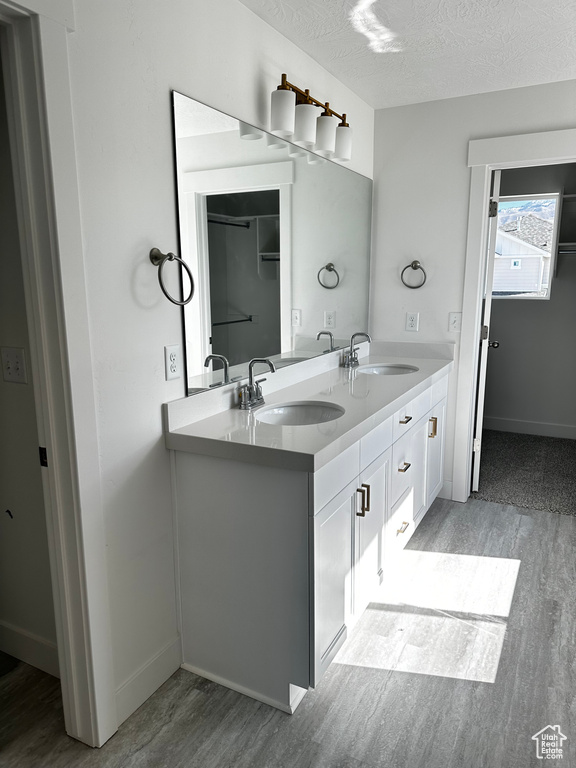 Bathroom featuring hardwood / wood-style floors, dual vanity, and a textured ceiling