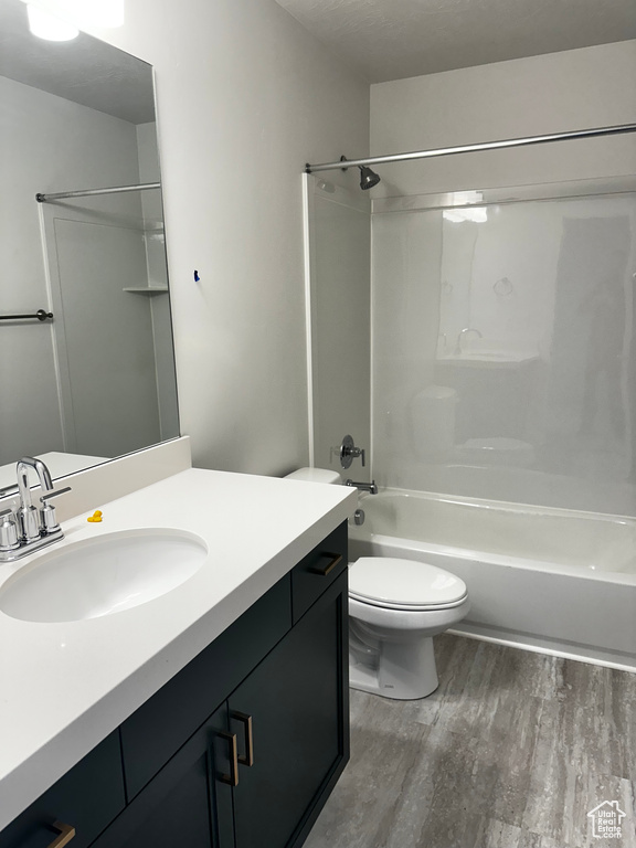 Full bathroom featuring hardwood / wood-style floors, shower / bathtub combination, vanity with extensive cabinet space, and toilet