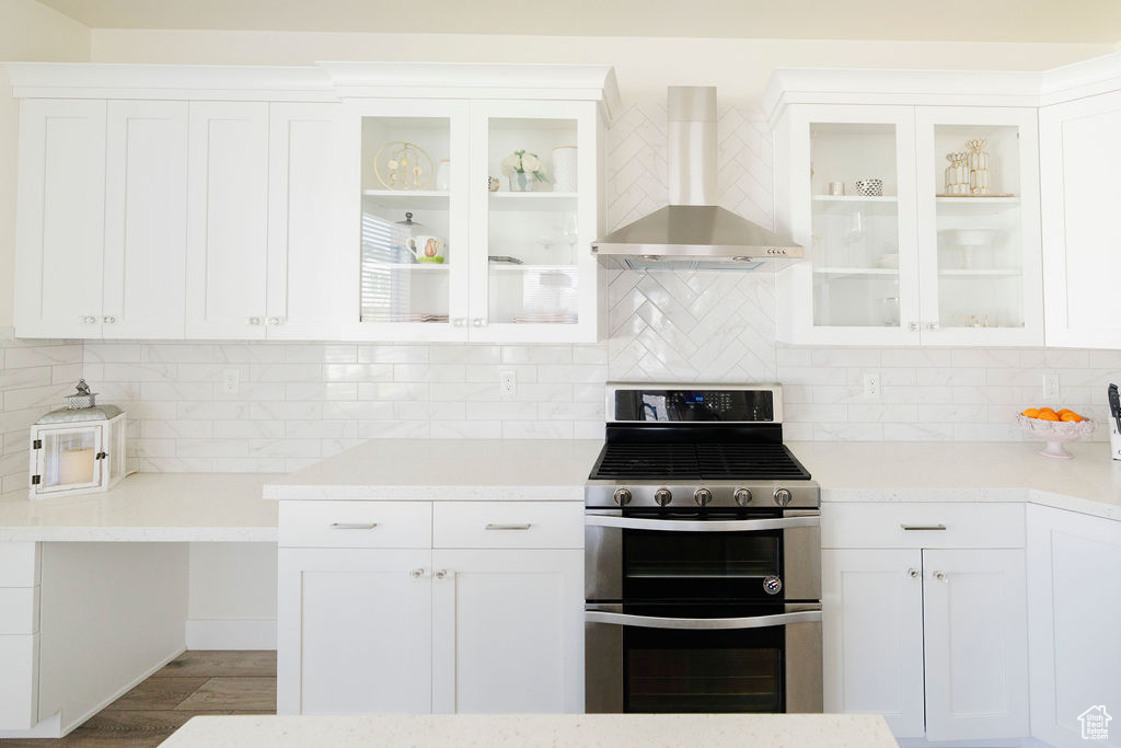 Kitchen featuring backsplash, stainless steel range with gas stovetop, and wall chimney exhaust hood