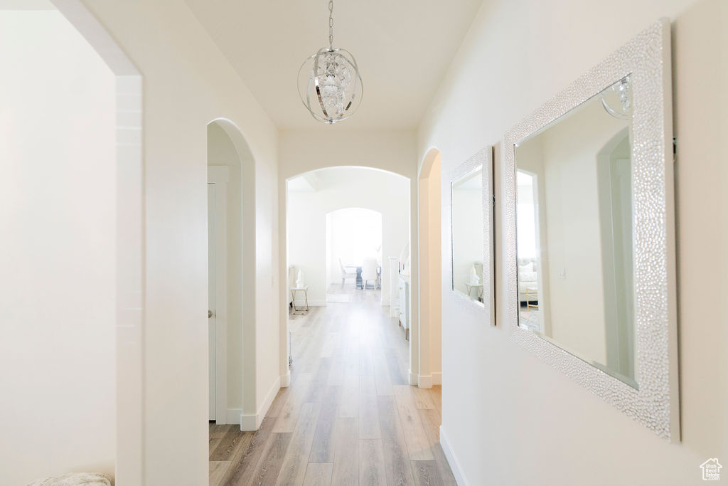 Hallway featuring light hardwood / wood-style floors and a chandelier