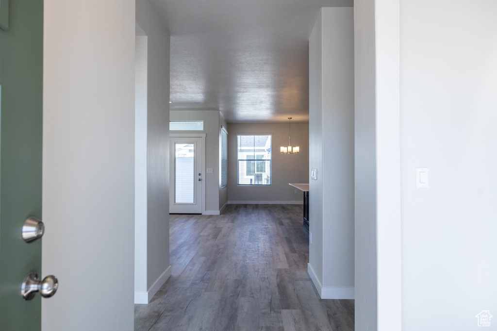 Hallway featuring dark hardwood / wood-style floors and a notable chandelier