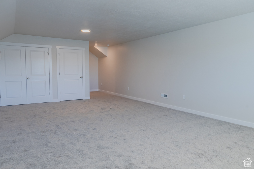 Unfurnished bedroom featuring vaulted ceiling and light carpet