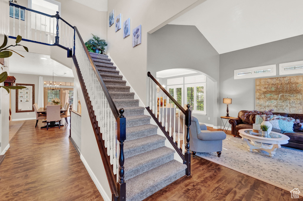 Stairs featuring dark hardwood / wood-style flooring, a high ceiling, and a notable chandelier