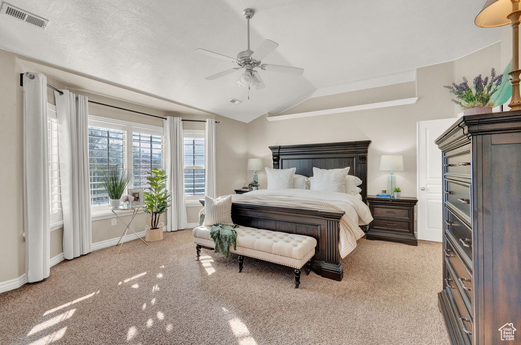 Bedroom featuring light colored carpet, lofted ceiling, ceiling fan, and a textured ceiling
