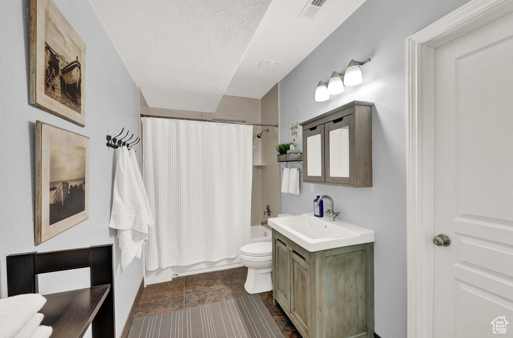 Full bathroom with tile flooring, shower / tub combo, toilet, and oversized vanity
