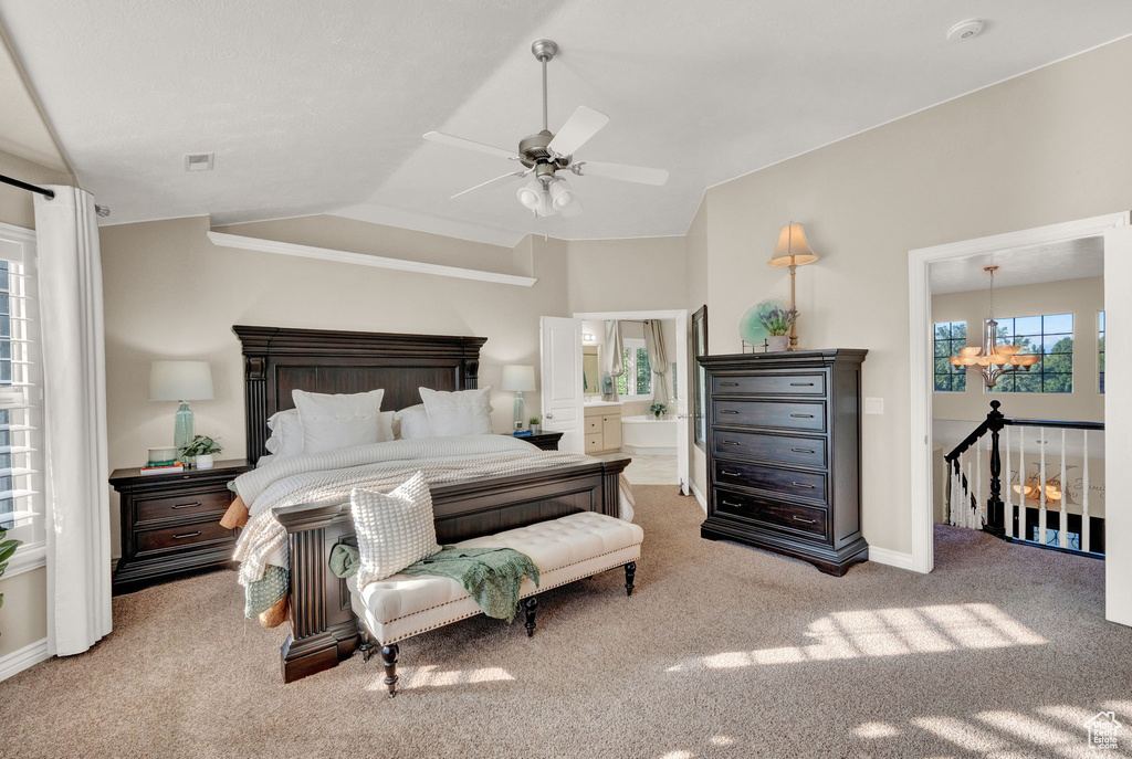 Bedroom with light colored carpet, ceiling fan with notable chandelier, vaulted ceiling, and ensuite bathroom