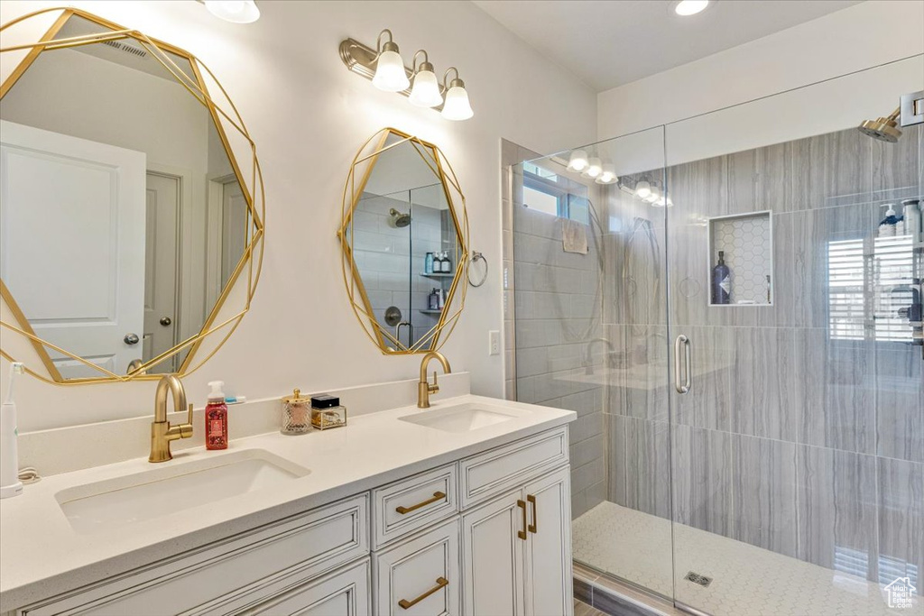 Bathroom with walk in shower, vanity with extensive cabinet space, and double sink