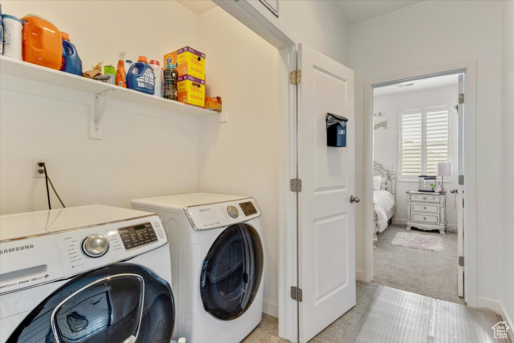 Washroom with light carpet and washing machine and clothes dryer
