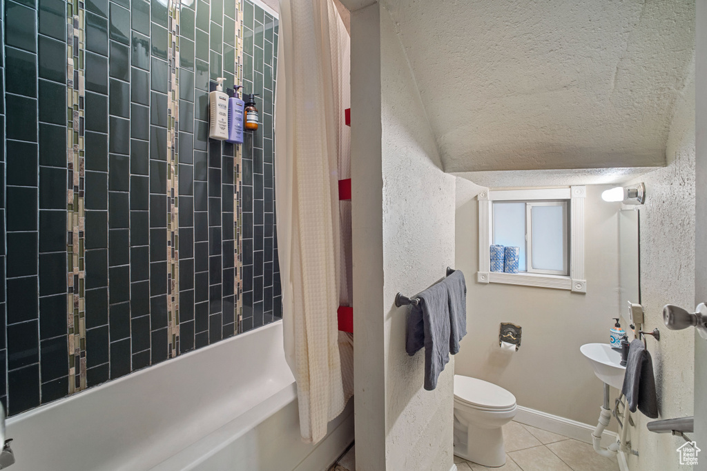 Bathroom with shower / bath combination with curtain, tile flooring, toilet, a textured ceiling, and lofted ceiling