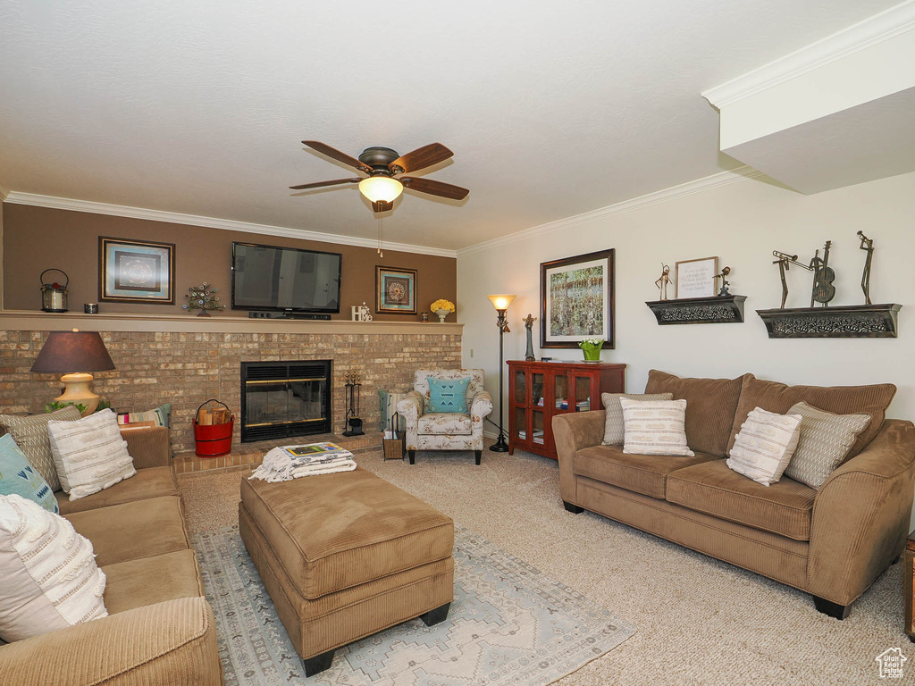 Carpeted living room with ceiling fan, crown molding, and a brick fireplace