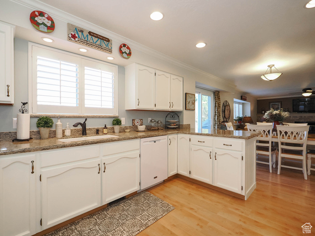 Kitchen with kitchen peninsula, light hardwood / wood-style floors, dishwasher, white cabinetry, and sink