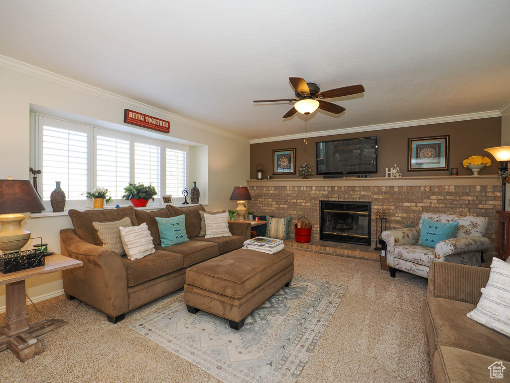 Carpeted living room with ceiling fan, a brick fireplace, and crown molding