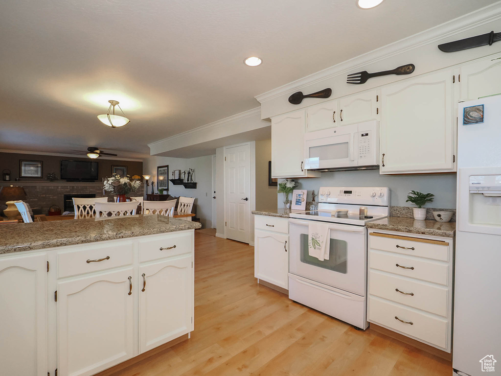 Kitchen with light hardwood / wood-style flooring, white appliances, ceiling fan, white cabinets, and ornamental molding
