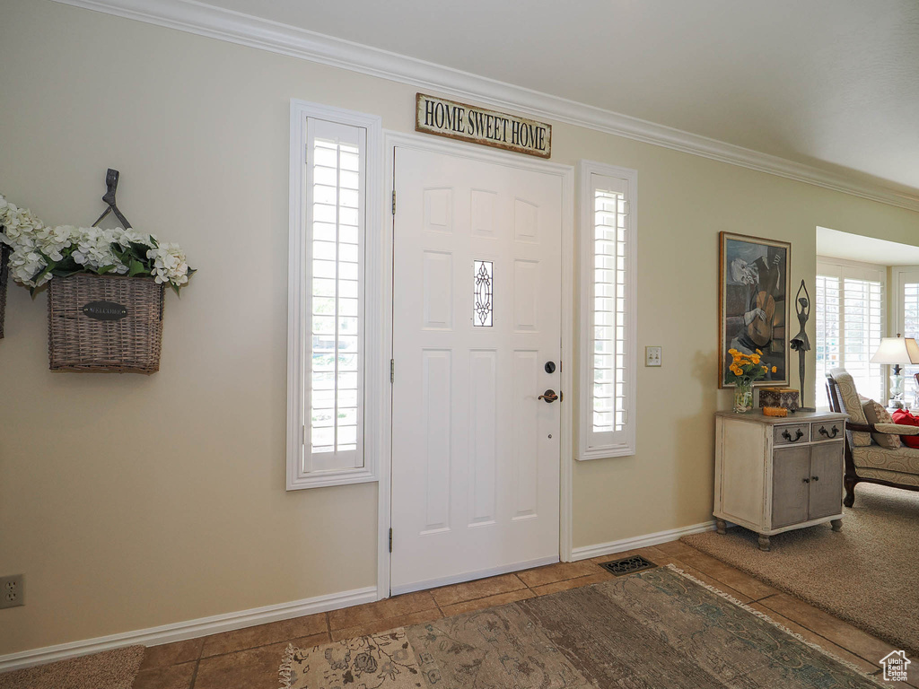 Entryway with a healthy amount of sunlight, tile floors, and ornamental molding