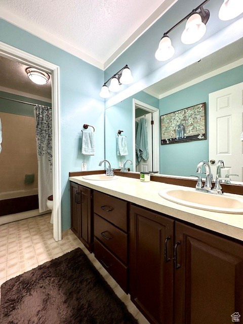 Full bathroom with a textured ceiling, tile floors, dual bowl vanity, and toilet