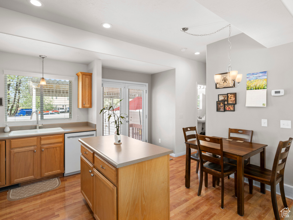 Kitchen featuring a center island, hanging light fixtures, white dishwasher, sink, and light hardwood / wood-style floors
