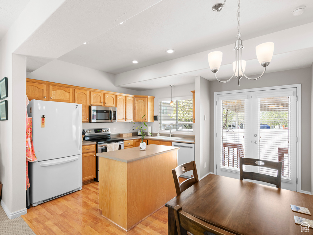 Kitchen featuring hanging light fixtures, a kitchen island, light wood-type flooring, and stainless steel appliances